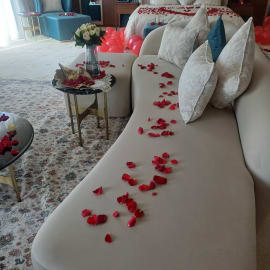 A romantic setting with a heart of rose petals and candles.