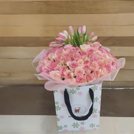 A close-up of a bouquet exploding with soft pink roses and cheerful pink tulips, symbolizing affection and joy.