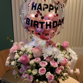 A beautiful flower box filled with pink roses, baby pink roses, baby white roses, chrysanthemums, and pink carnations arranged with ruscus leaves.