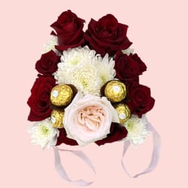  Red roses with an elegant big Pink rose and a filling of chrysanthemum and Ferrero Rocher chocolate balls in a Pink Bucket.