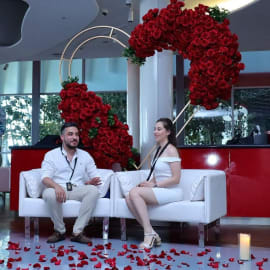 Couple embracing in front of floral heart arch

