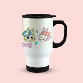 A white travel mug with a black handle and lid, featuring a colorful illustration of a monster character in a blue hat and another in a pink hat, along with the partial word 