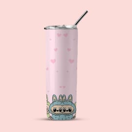 A pink tumbler with small pink hearts and a blue monster in a bunny suit at the bottom, shown with a lid and straw against a light pink background.