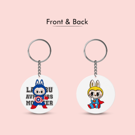 A side-by-side view of a circular plastic keychain showing its front and back. The front features Labubu as Captain America, while the back shows him as Superman.