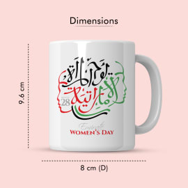 A close-up shot of a white ceramic mug with an Arabic calligraphy design and the text 