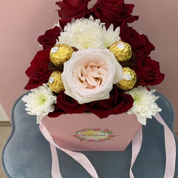  Red roses with an elegant big Pink rose and a filling of chrysanthemum and Ferrero Rocher chocolate balls in a Pink Bucket.