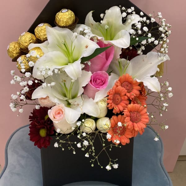 Graduation Floral Box of lilies, Pink Roses and Gerbera. Ferrero Rocher chocolate balls and gypsophila filling in a black box.