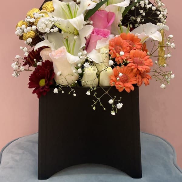 Graduation Floral Box of lilies, Pink Roses and Gerbera. Ferrero Rocher chocolate balls and gypsophila filling in a black box.