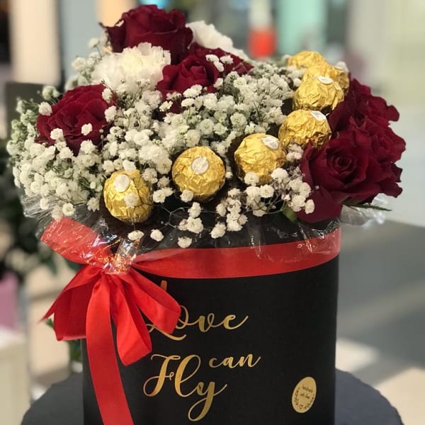 In a black box, red roses and white carnations with gypsophila filling and Ferrero Rocher toppings. 