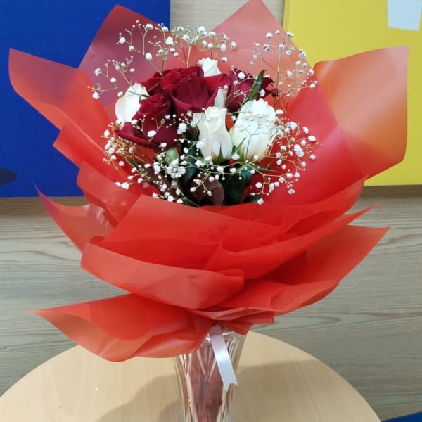 Red and white roses bouquet in a glass vase - a symbol of love and purity.