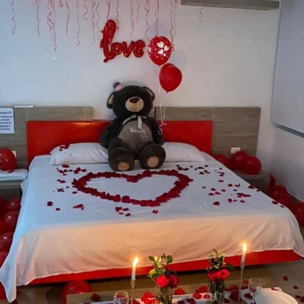 Romantic room decor with red balloons and rose petals