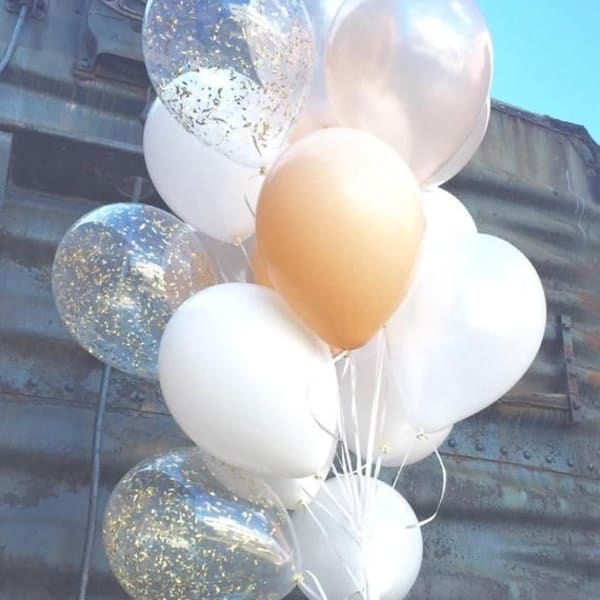 Assorted helium balloons in white, golden, and transparent colors