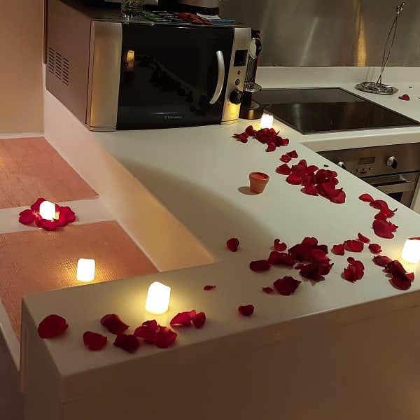 Heart-shaped rose petal arrangement on bed with candles