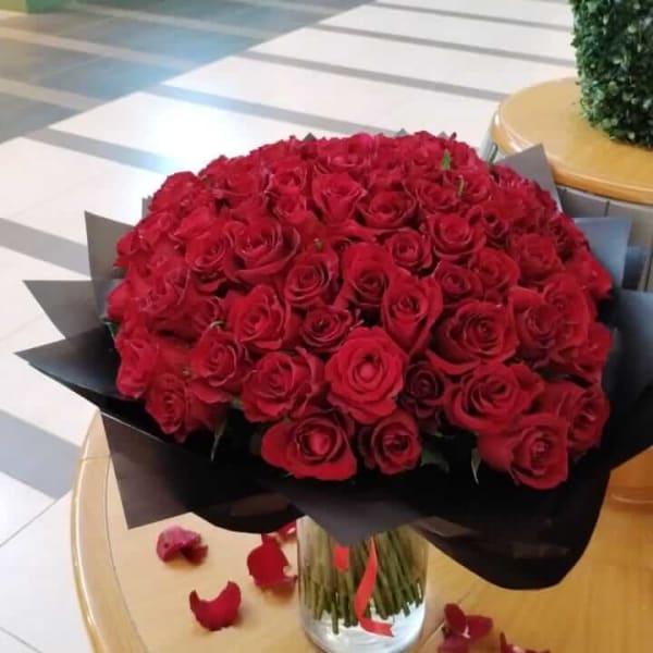 A hundred fresh red roses arranged beautifully in black wrapping.