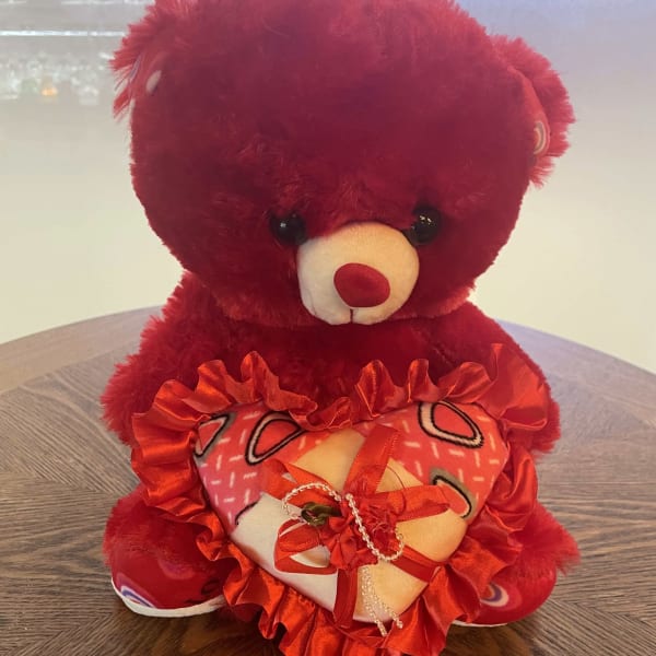Red teddy bear holding heart, perfect floral gift companion.