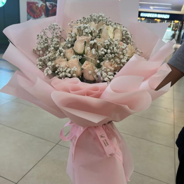 A bouquet of warm peach roses intertwined with delicate white baby's breath.