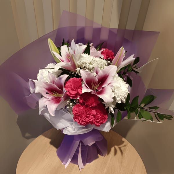 Pink lilies and baby's breath bouquet arranged in a vase.
