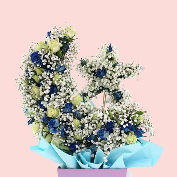 Close-up of a moon and star-shaped arrangement with white and blue roses, accented with delicate gypsophila.