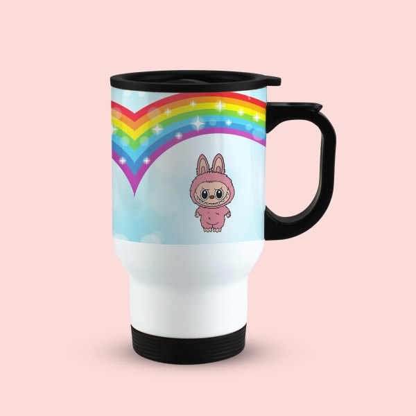 A white travel mug with a black handle and lid, featuring a pink monster character under a rainbow arch.