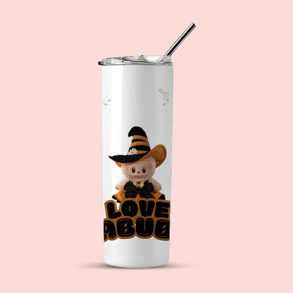 A white insulated tumbler with a black straw, featuring a plush character in a witch's hat above text and subtle ghost-like figures in the background.