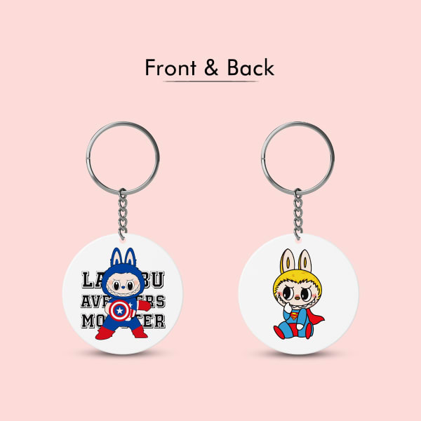 A side-by-side view of a circular plastic keychain showing its front and back. The front features Labubu as Captain America, while the back shows him as Superman.