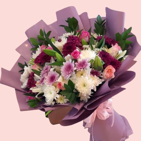  A full view of the Floral Bliss Bouquet, highlighting the intricate arrangement of lilies, chrysanthemums, and roses in a purple paper wrap.