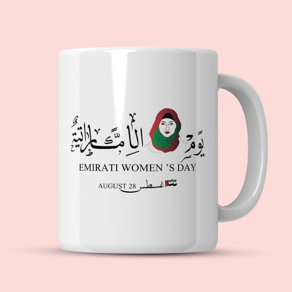 A white ceramic mug with an Arabic calligraphy design and a stylized woman's portrait, celebrating Emirati Women's Day.