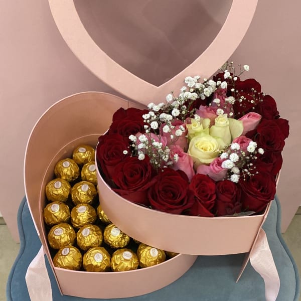 Fresh Red, White, and Pink Roses in a heart shape manner in a heart box with Ferrero Rocher chocolates beneath it.  