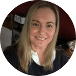 smiling woman with long blonde hair in a black sweater against a kitchen background, bright and friendly home environment portrait