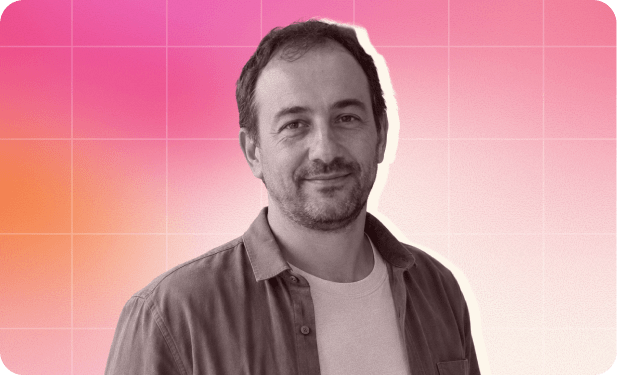 portrait of a man with short hair, smiling against a pink and orange gradient background, man in casual attire, vibrant backdrop