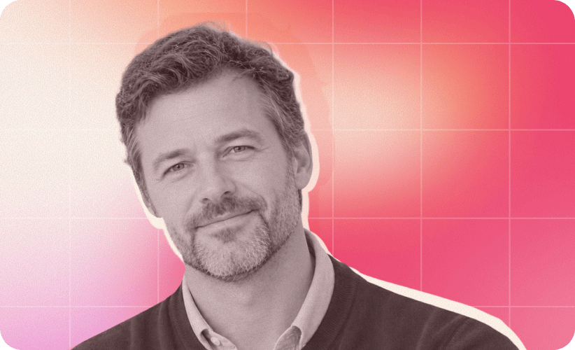 man with beard smiling against a vibrant pink gradient background, portrait of a man in a sweater with a friendly expression