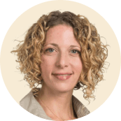 woman with curly hair smiling, professional headshot on neutral background