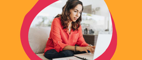 woman working on laptop in modern workspace, wearing red blouse, focused and engaged, comfortable indoor setting with bright colors