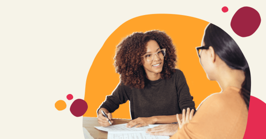 smiling woman with curly hair discussing documents, two women collaborating at a table with vibrant background elements