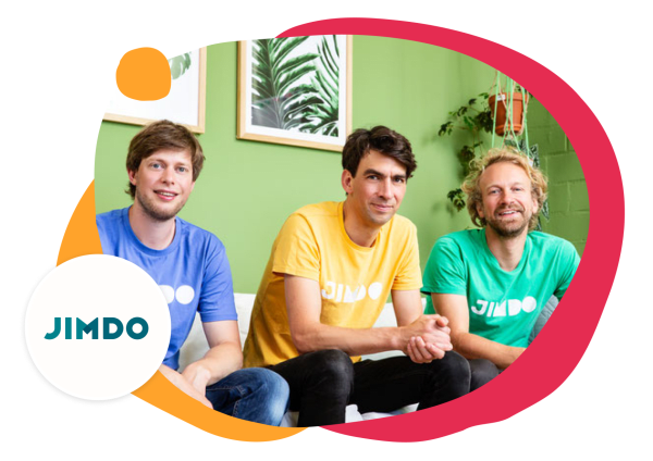 JIMDO team members in colorful shirts, posing against a green background with plants and framed artworks., JIMDO, team_photo