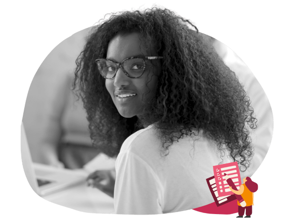 smiling woman with curly hair and glasses looking back at laptop, creative workspace setting with digital elements