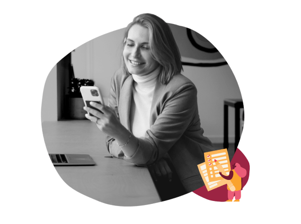 smiling woman in blazer uses smartphone at desk, with laptop nearby and creative note illustration, office setting with technology focus