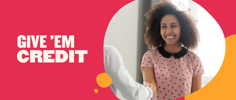 smiling woman in pink shirt shaking hands with a professional in white shirt, vibrant background with text GIVE 'EM CREDIT, business handshake, positive interaction