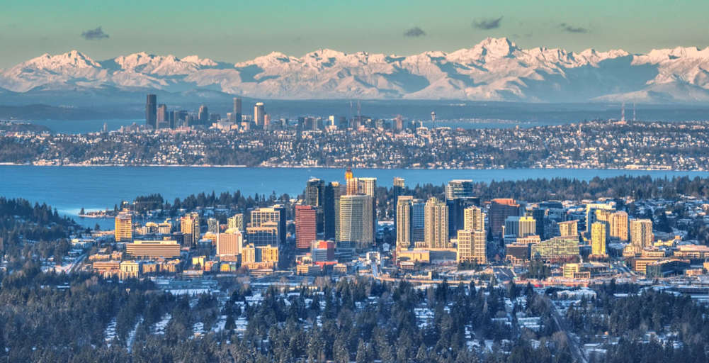 Dawn light over downtown Bellevue, with snow covered Olympic mountains, downtown Seattle, and Lake Washington in the background, in Washington state.