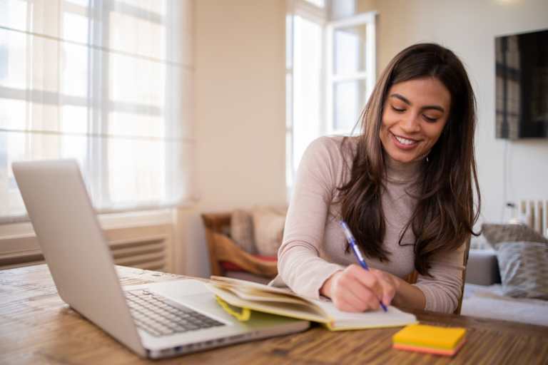 Female college student doing coursework on her laptop computer at home.