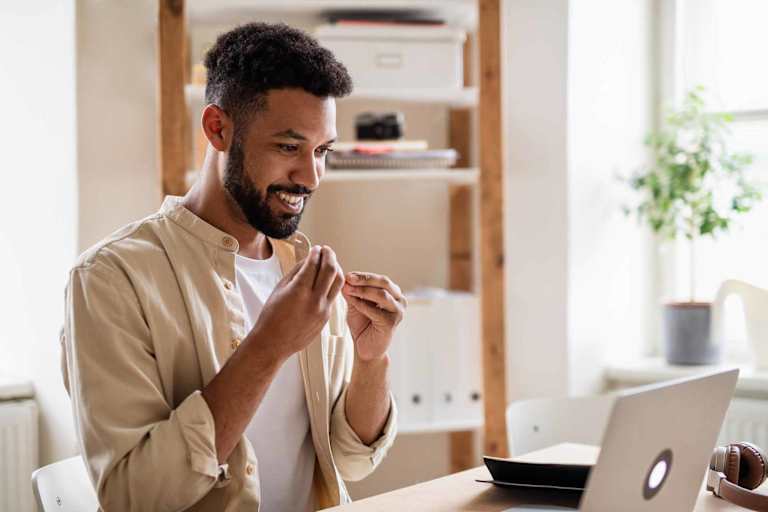 Young man with laptop using sign language indoors in office