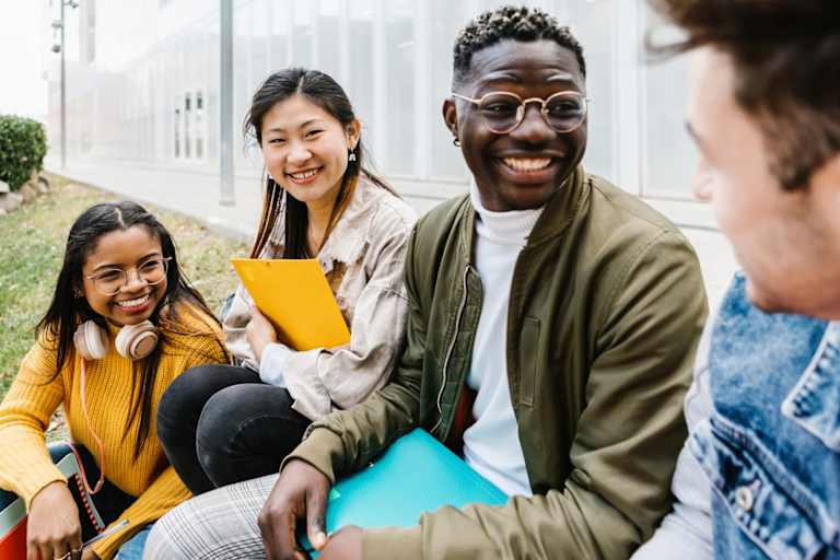 Multiethnic group of young student friends hanging out at university campus - Asian teenage girl is smiling at camera - International erasmus exchange concept
