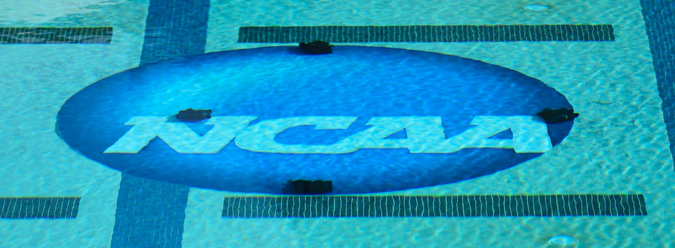 The NCAA Logo photographed from above. The logo is on the bottom of a collegiate swimming pool.
