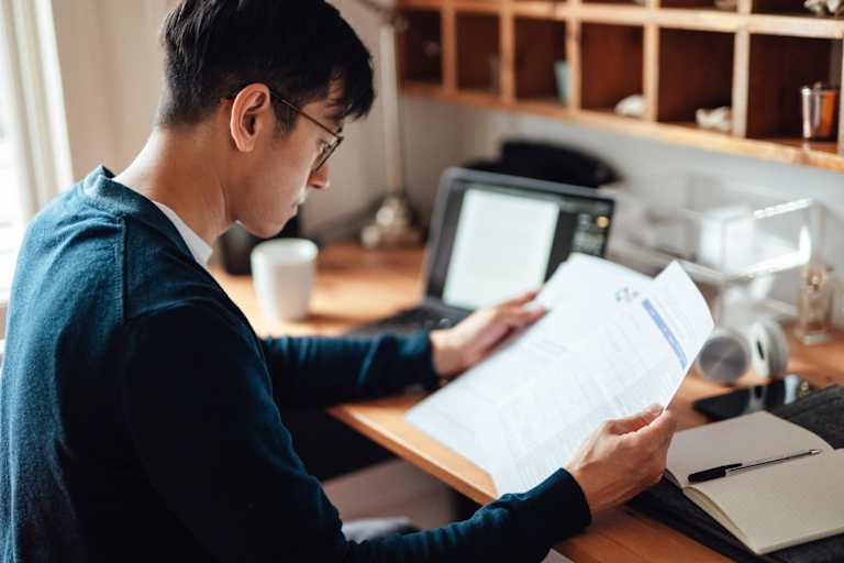 Student looking through paperwork in home office