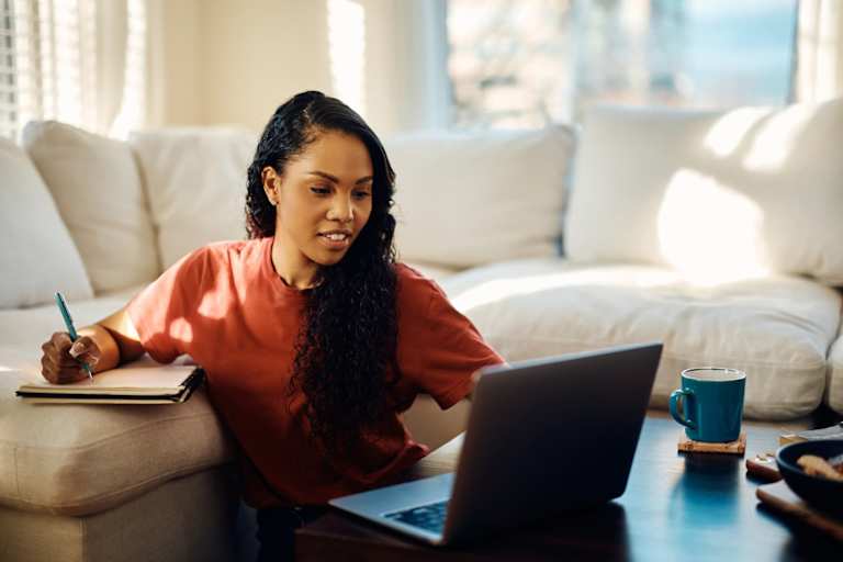 Student at home working on laptop and taking notes