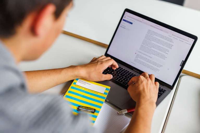 A college student sits in front of a laptop and uses an AI chatbot to help him complete a German language assignment.