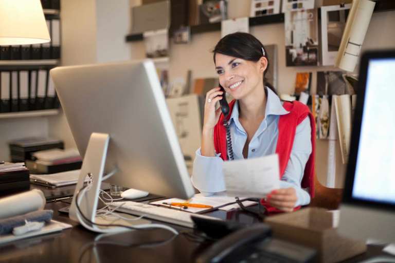 CPA sitting at desk in office answering her phone