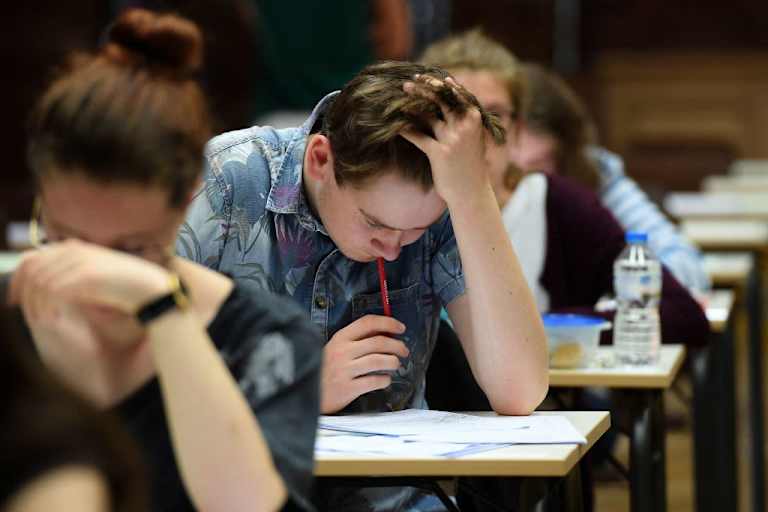High school students taking a paper exam in a classroom.