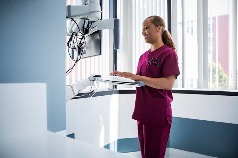 Smiling female nurse working on computer in hospital