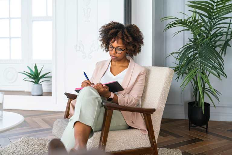 Psychologist writing with pen in diary at office